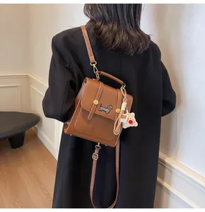 Detail of brown leather crossbody bag featuring dachshund embroidery and plush bear charm