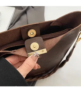 Detailaufnahme der braunen Ledertasche mit goldenem Magnetverschluss und Flechtriemen