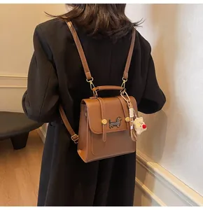 Detailed view of brown leather backpack with dachshund embroidery and white plush charm