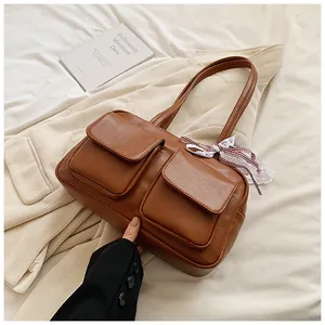 Close-up of caramel tote bag with double front pockets and decorative ribbon accent