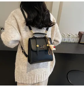 Detail of black faux leather mini backpack featuring embroidery and a plush bear charm
