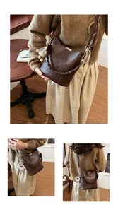 Detail der dunkelbraunen geflochtenen Eimertasche mit Metallschnalle und Bärenanhänger