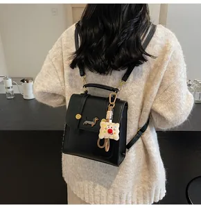 Detail of a black leather mini backpack with a dachshund patch and plush bread charm
