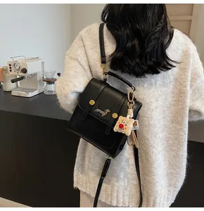 Detail of mini black leather backpack with dachshund embroidery and plush charm pendant