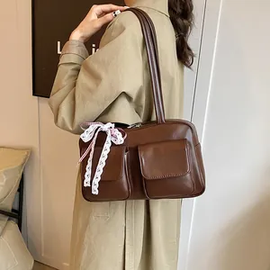 Retro large brown tote bag with side pockets and lace bow decoration shown on shoulder