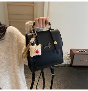 Detail of black leather backpack with dachshund patch and plush dog charm accessory