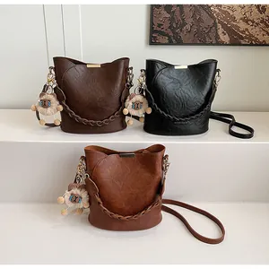 Detailansicht der gewebten Leder-Eimertaschen in Braun und Schwarz mit Plüschanhängern