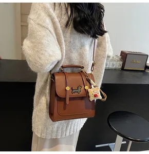 Brown leather crossbody bag with dachshund patch and plush biscuit charm detail