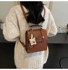 Brown faux leather mini backpack featuring dachshund embroidery and plush charm on a model