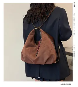 Detail of dark brown matte leather hobo bag with woven charm and large capacity