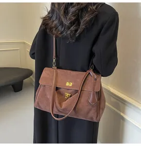 Borsa tote in pelle smerigliata marrone con chiusura girevole oro indossata da una modella