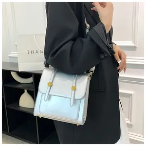 Détail d'un sac bandoulière argenté à clous dorés porté par un mannequin en costume noir