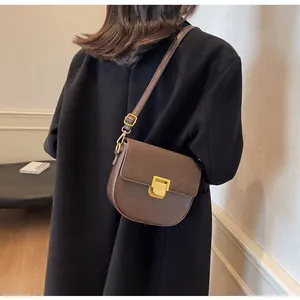 Dettaglio borsa a sella marrone vintage su modella con fibbia dorata e trama opaca