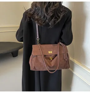 Dettaglio borsa a tracolla in pelle scamosciata marrone con chiusura in metallo e tracolla