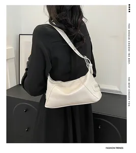 Close-up of white glossy shoulder bag showing the wide strap and decorative side zipper