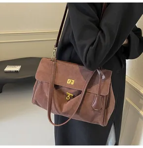Dettaglio della borsa a spalla in camoscio rosso-marrone con chiusura a scatto dorata