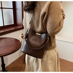 Detail der dunkelbraunen Beuteltasche mit Flechtgriff und süßem Bär-Anhänger