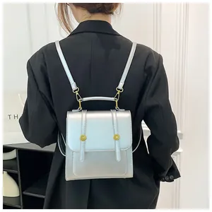 Détail d'un sac à dos argenté métallisé avec boucle dorée porté sur un tailleur noir
