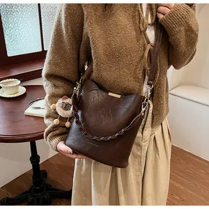 Detail der dunkelbraunen Leder-Eimertasche mit Kettenhenkel und Löwen-Plüschanhänger