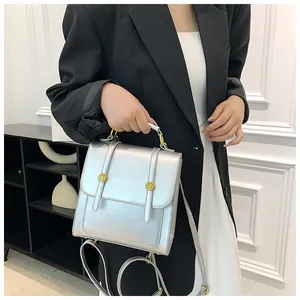 Détail du sac à dos argenté métallisé avec boucles dorées et poignée sur modèle