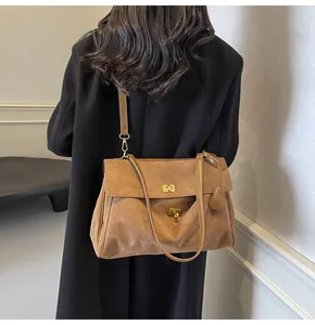 Borsa moderna in pelle scamosciata color caramello indossata con un cappotto nero