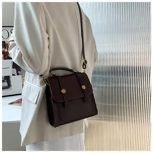 Vue détaillée du sac à main en cuir marron foncé avec boucles dorées et poignée solide