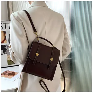 Détail du sac à dos convertible en cuir marron foncé avec boucles dorées et bandoulière