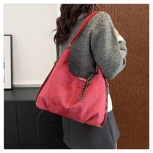 Detail of dark red suede hobo bag with zip closure and woven puller decoration