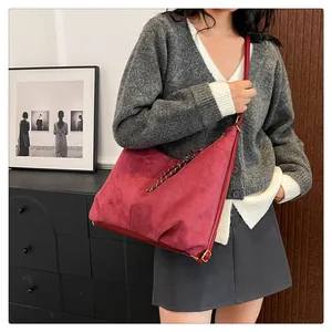 Close-up of red suede tote bag with woven rope zipper detail and metal buckle