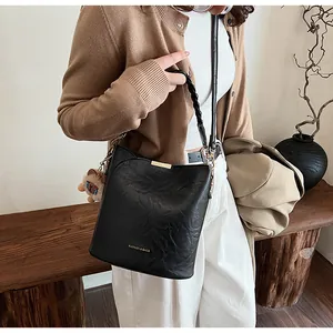 Detail der schwarzen geflochtenen Beuteltasche mit Vintage-Struktur und Löwenanhänger