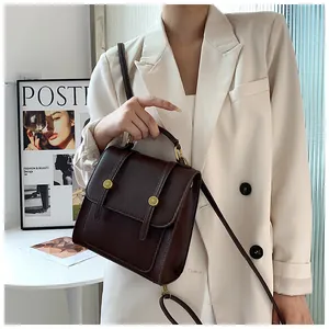 Détail d'un sac à main vintage en cuir marron avec boucles dorées cylindriques chic