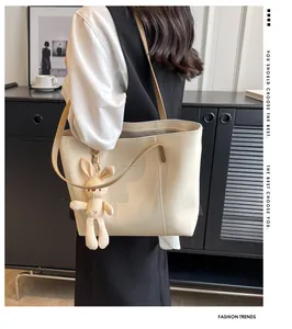 Minimalist cream tote bag with brown straps and cute plush rabbit charm detail