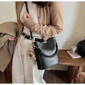Detailansicht einer schwarzen Eimertasche mit Webgriff, Bärenanhänger und Goldbeschlägen