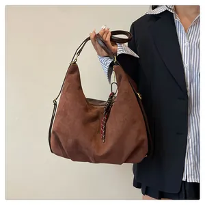 Detail of vintage brown suede hobo bag with adjustable leather strap and woven lanyard