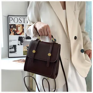 Détail d'un sac en simili cuir marron foncé avec boucles dorées et poignée robuste