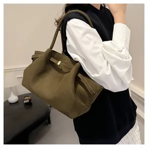 Dettaglio della borsa tote verde scuro opaco con fibbia dorata indossata dalla modella