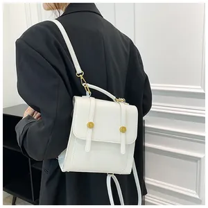 Modèle portant un sac bandoulière blanc minimaliste avec finitions dorées sur veste