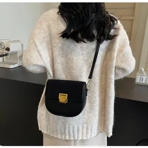 Dettaglio ravvicinato di una borsa a sella in pelle nera opaca con grande fibbia dorata