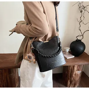 Detail der schwarzen geflochtenen Eimertasche mit Goldakzenten und Plüschbär-Anhänger