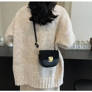 Dettaglio della borsa a sella nera con fibbia dorata indossata a tracolla moda