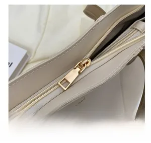 Close-up of golden rectangular zipper and fashion trend text on off-white tote bag