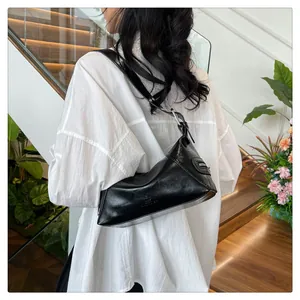 Detail of a black glossy shoulder bag with silver metal ring and side pocket design