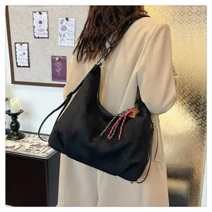 Detail of a black matte hobo bag with braided red rope charm and metal key accessory