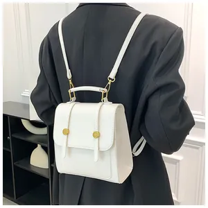 Mini sac à dos blanc en cuir PU avec rivets dorés porté par un mannequin en blazer