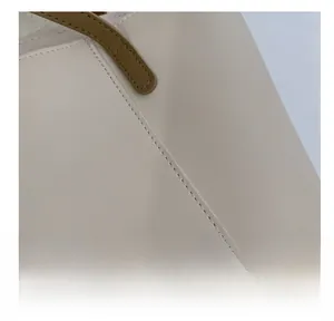 Macro shot of precise stitching on beige leather tote bag with brown handles