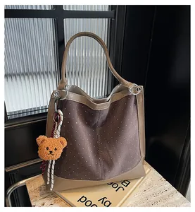 Detail of vintage suede bucket bag with white polka dots and cute teddy bear charm