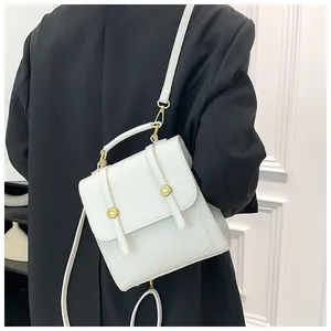 Vue arrière du modèle portant un sac à dos blanc structuré avec boucles dorées et sangles