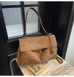 Dettaglio della borsa in pelle scamosciata marrone con chiusura a scatto dorata