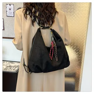 Detail of black suede hobo bag featuring decorative woven rope charms and silver hardware