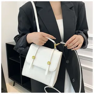 Vue détaillée d'un sac à main carré en cuir blanc porté par un mannequin en extérieur
